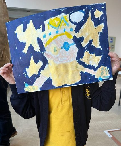 A child holds a picture in front of his face.